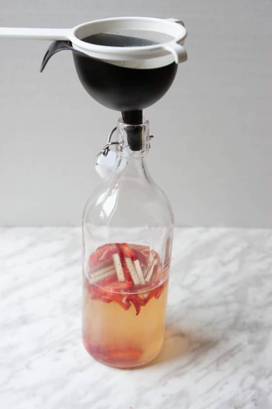 Flip-top bottle half-filled with kombucha, strawberries and rhubarb