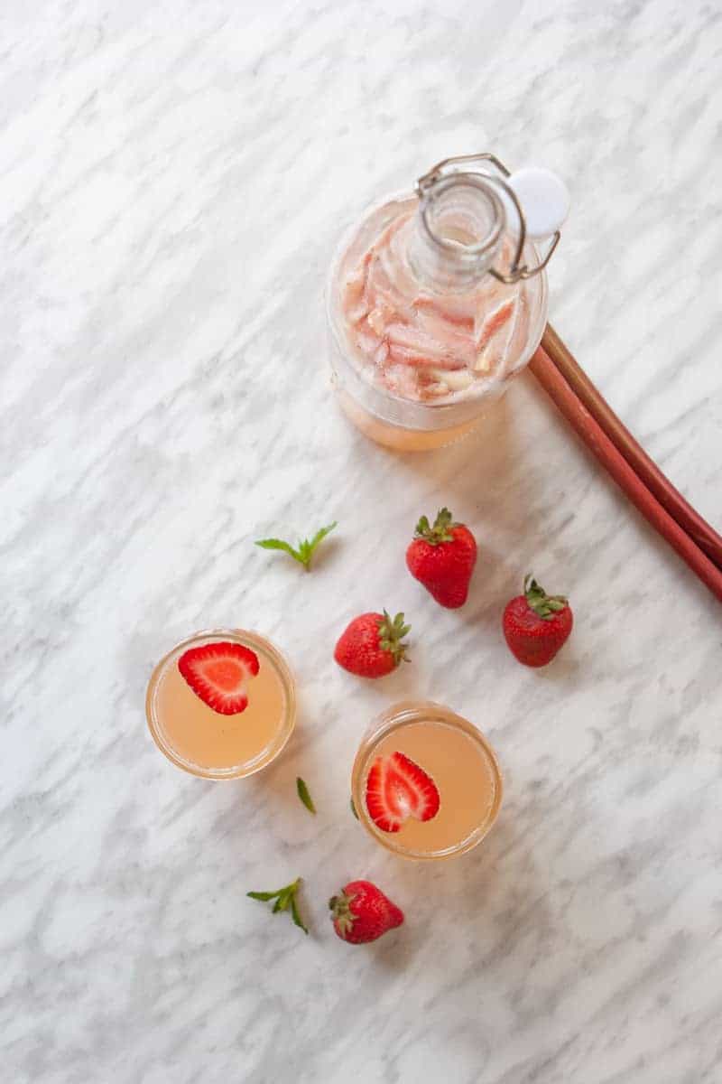 Open bottle of strawberry rhubarb kombucha with glasses
